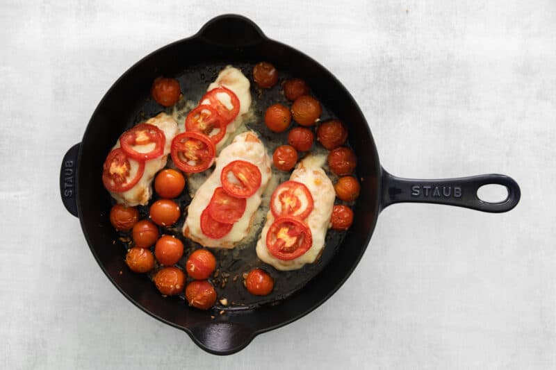 chicken and tomatoes in a cast iron skillet.