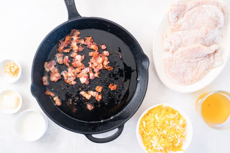 bacon crumbles cooking in a cast iron skillet.