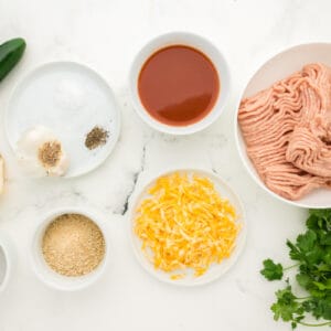 overhead view of ingredients for chicken enchilada meatballs in individual bowls.