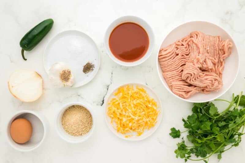 overhead view of ingredients for chicken enchilada meatballs in individual bowls.