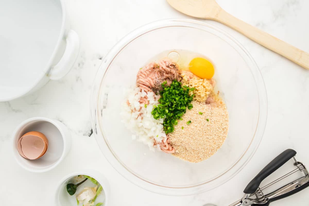 Chicken meatball ingredients in a glass mixing bowl.