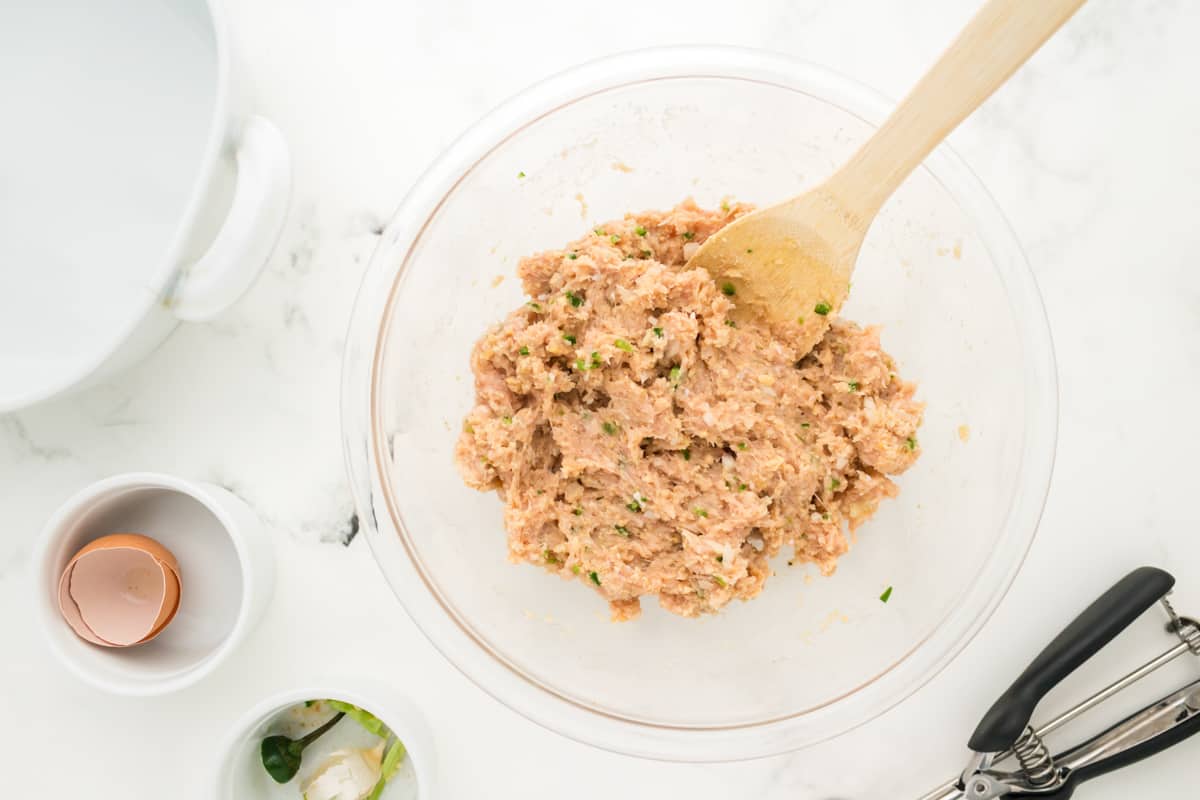 Ground chicken meatball mixture in a glass bowl.