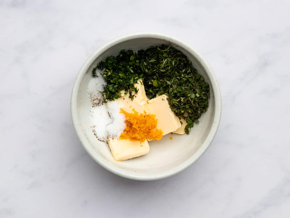 herb butter ingredients for christmas chicken in a white bowl.