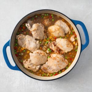 chicken stew with peas and peas in a blue pan.