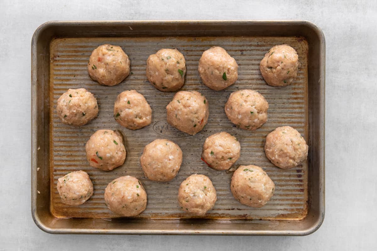 Sweet chili meatballs arranged on a baking sheet, unbaked.