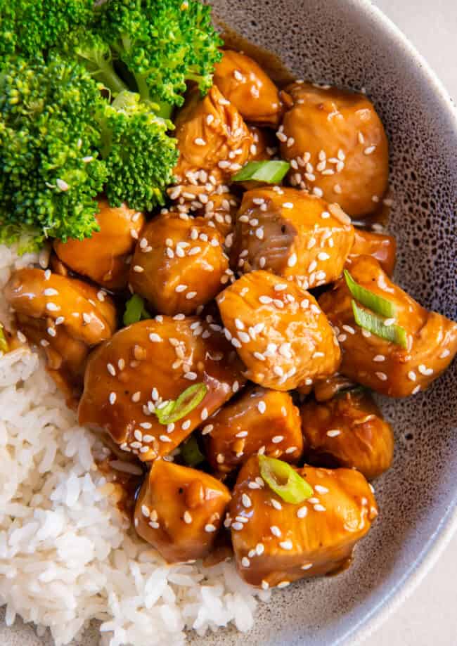 close up view of mandarin chicken in a gray bowl with rice and broccoli.