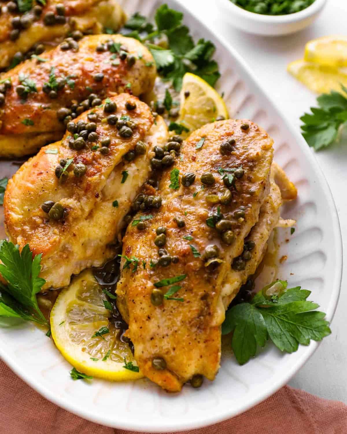 chicken piccata stuffed chicken breasts on a serving platter with lemon slices and parsley.