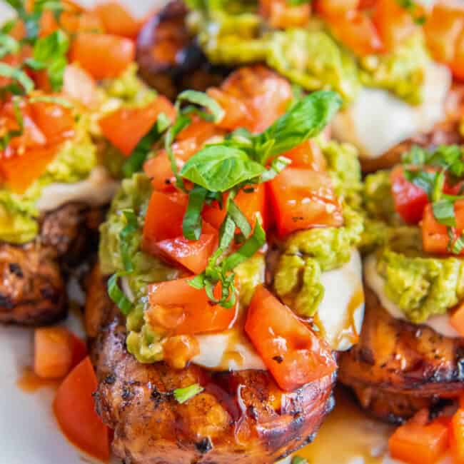 three-quarters view of 4 california grilled chicken breasts on a white plate.