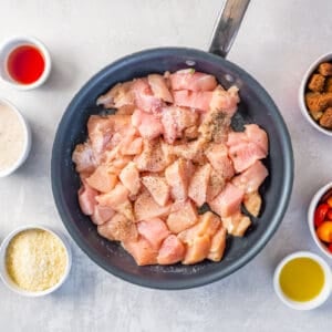 cubed raw chicken in a frying pan.