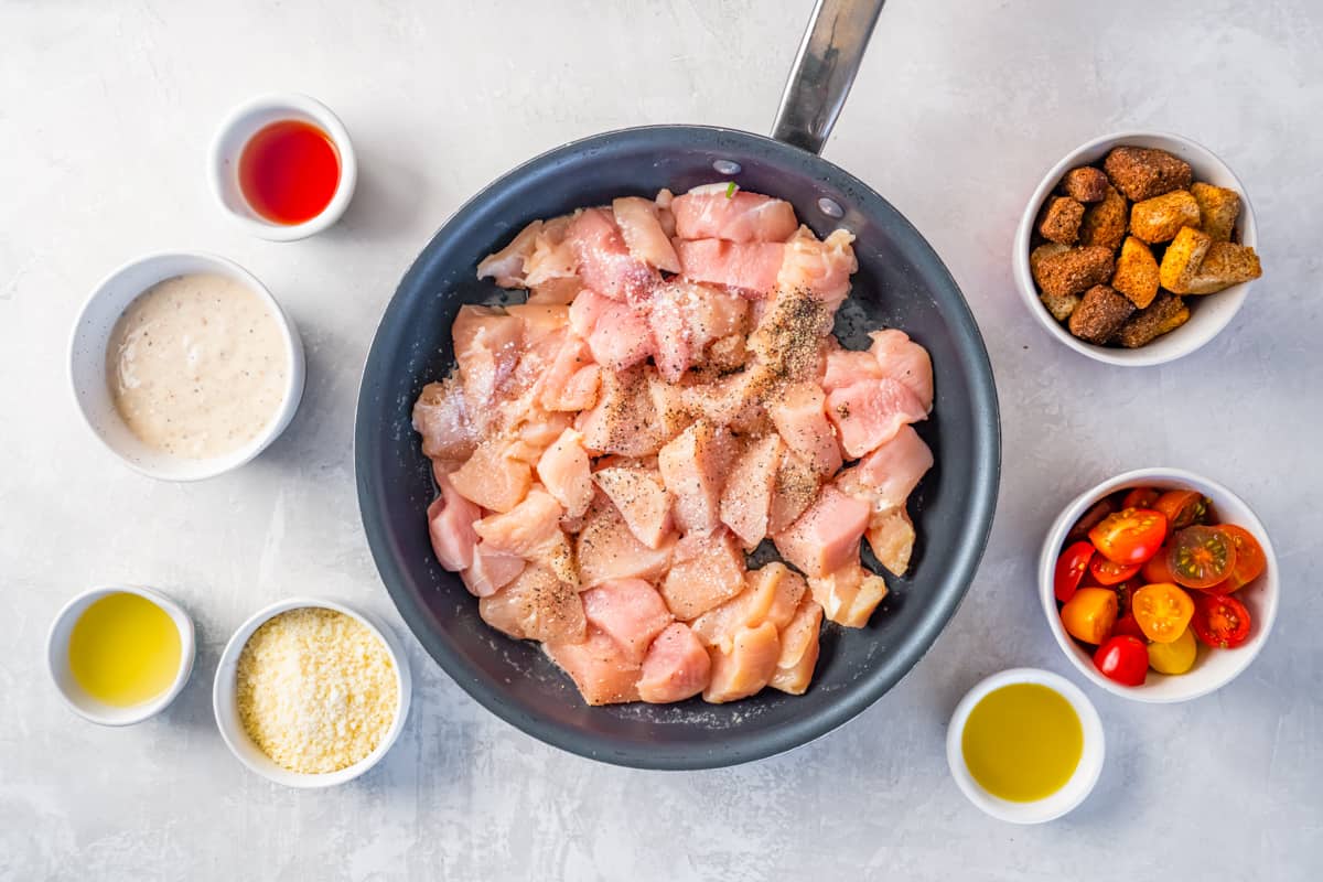 Cubes of raw chicken in a skillet.