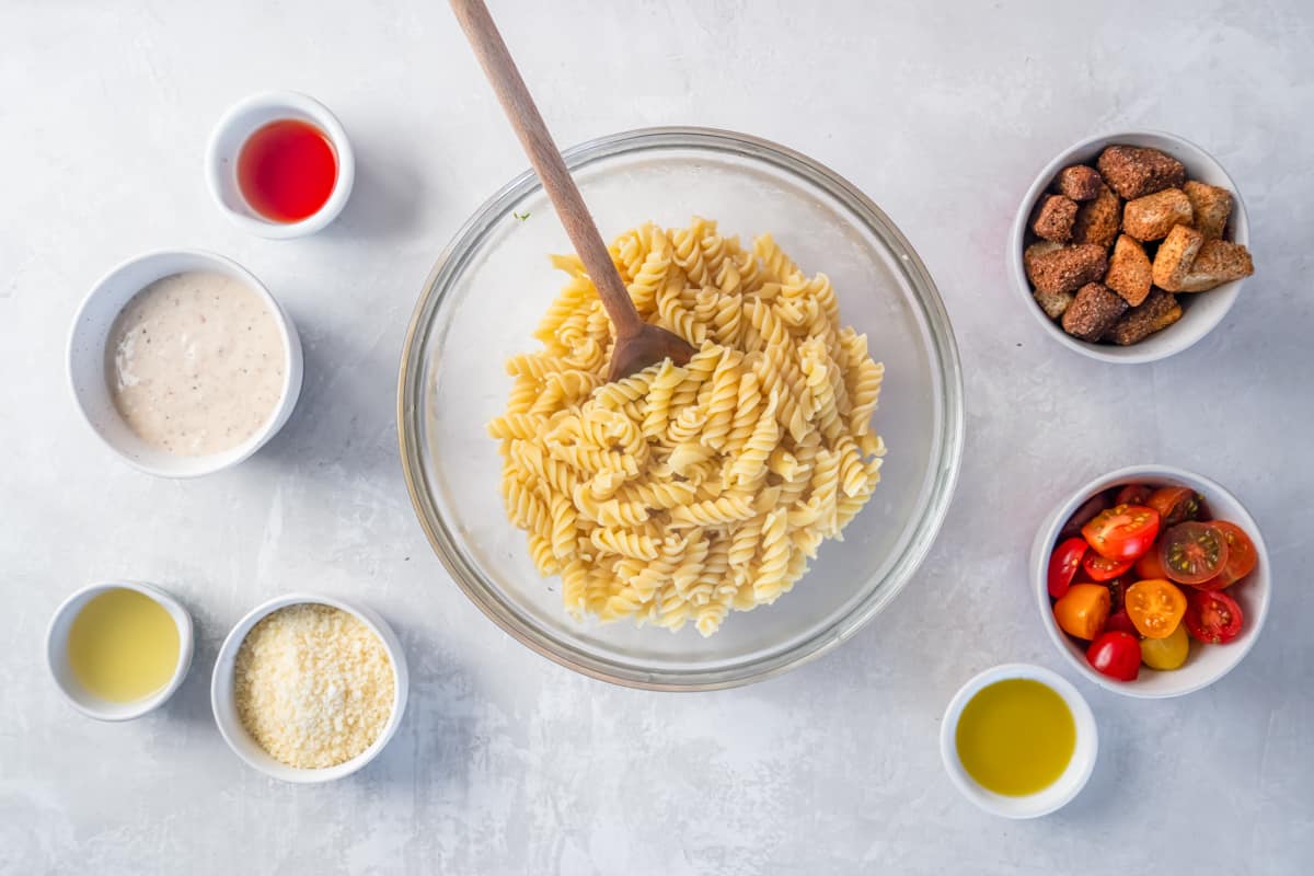 cooked pasta in a glass bowl with a wooden spoon.