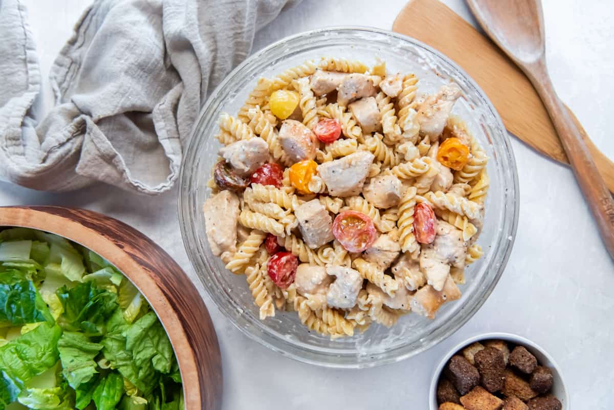 Chicken caesar pasta salad in a glass bowl.