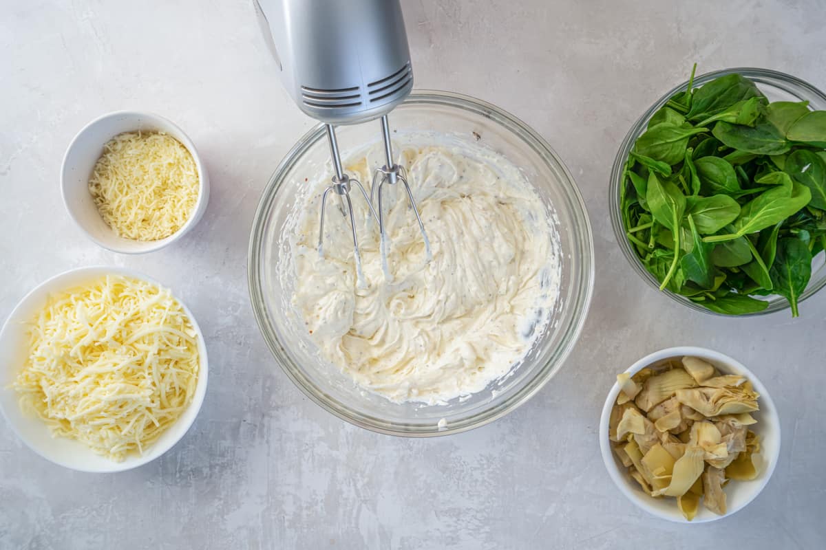 cream cheese mixture in a glass bowl with a hand mixer.