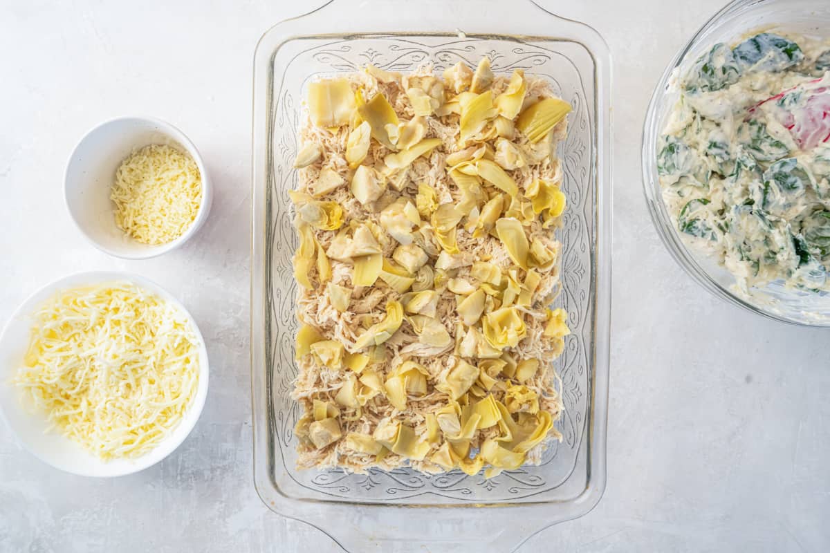 shredded chicken and artichoke in a rectangular casserole dish.