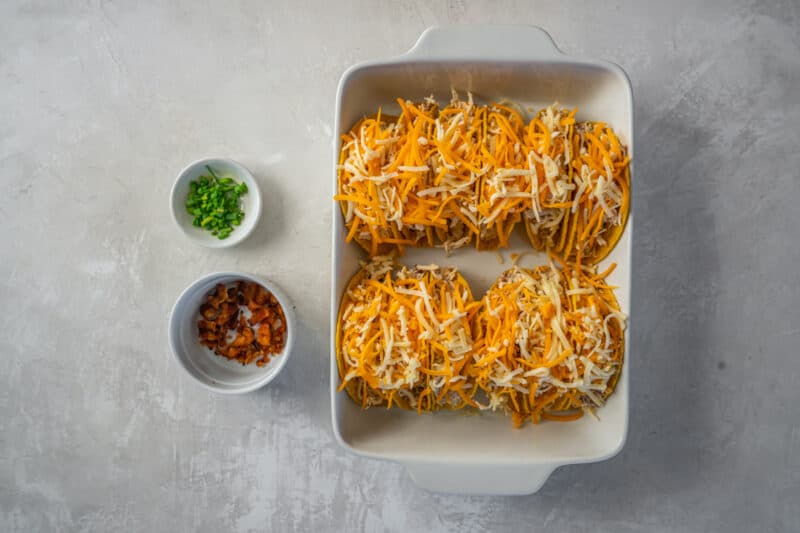 cheese sprinkled over crack chicken tacos in a rectangular white baking pan.