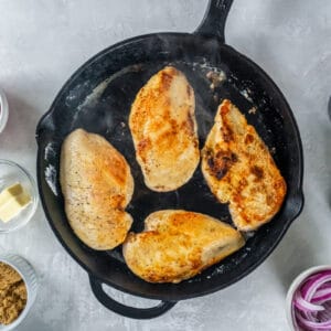 4 browned chicken breasts in a cast iron pan.