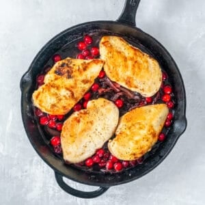 chicken added to sautéed onions and cranberries in a cast iron skillet.