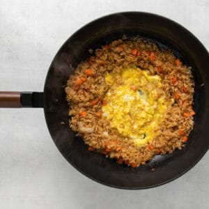 egg added to fried rice in a wok.