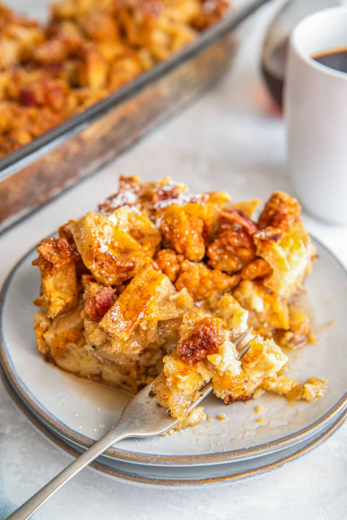 three-quarters view of a partially-eaten slice of chicken and waffle casserole on a white plate with a fork.