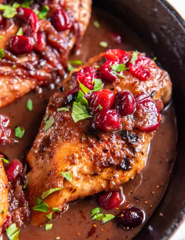 overhead close up view of a cranberry chicken breast in a cast iron skillet.