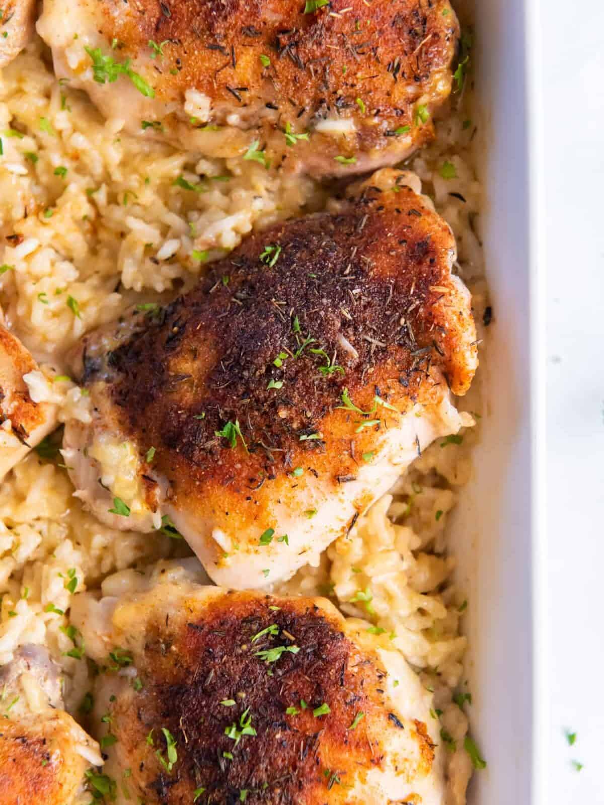 close up overhead view of baked chicken and rice in a casserole dish.