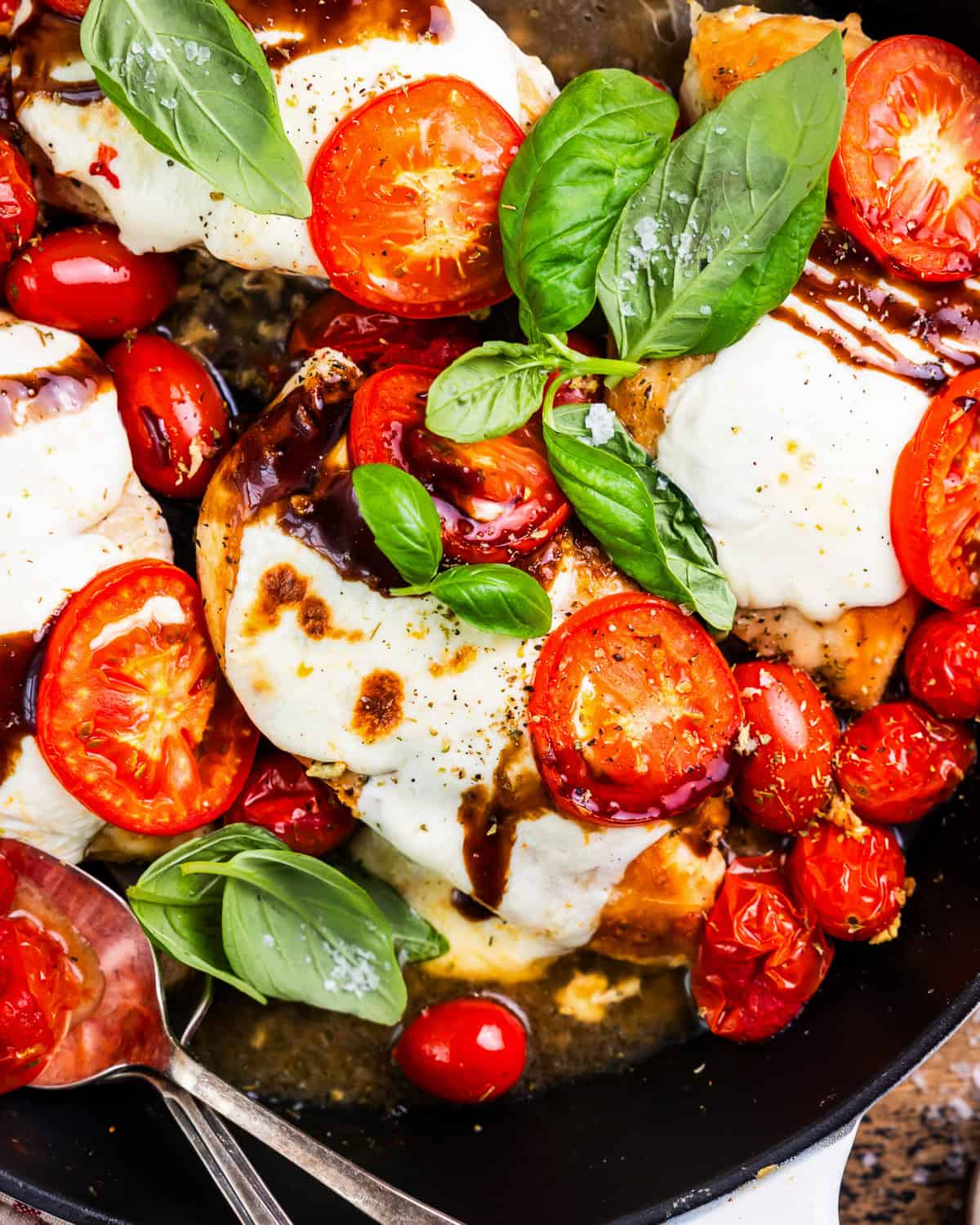 close-up overhead view of chicken caprese in a skillet.