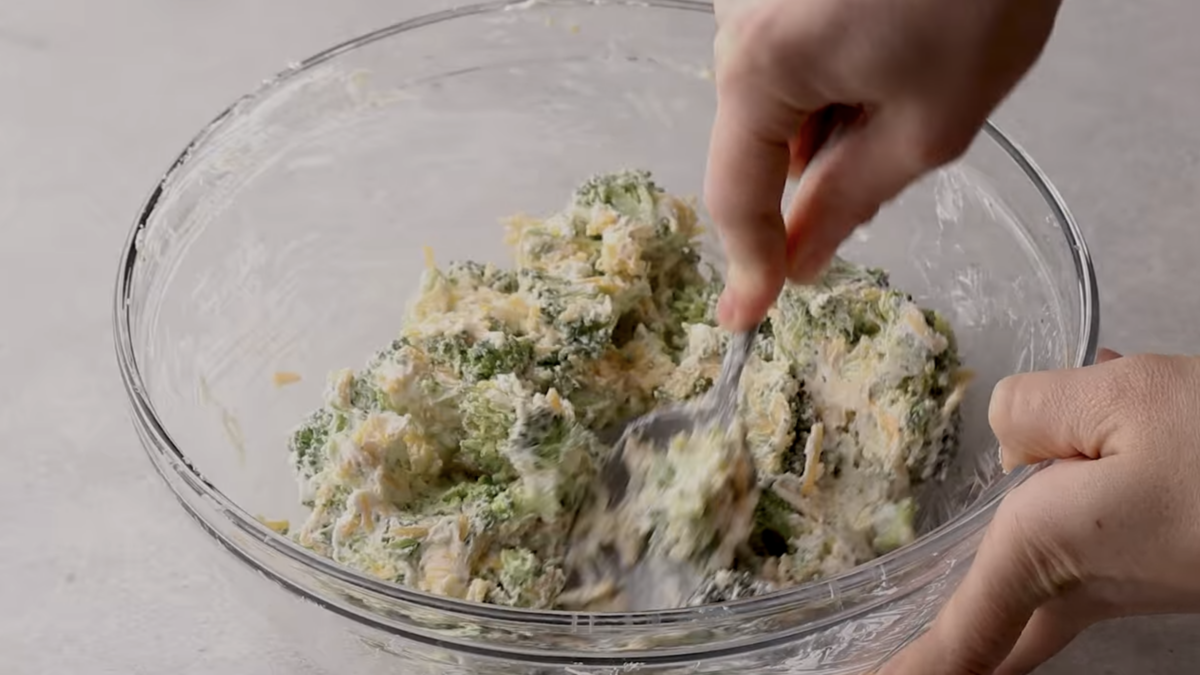Broccoli cheese filling is being mixed in a bowl. 