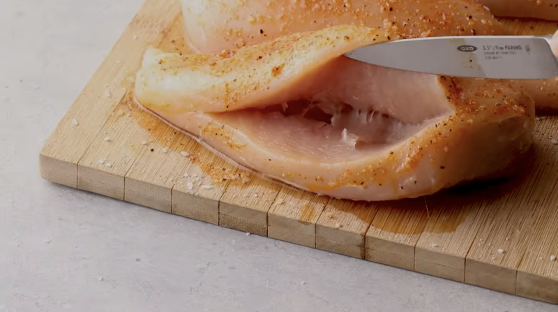 A raw chicken breast has been sliced to create a pocket.