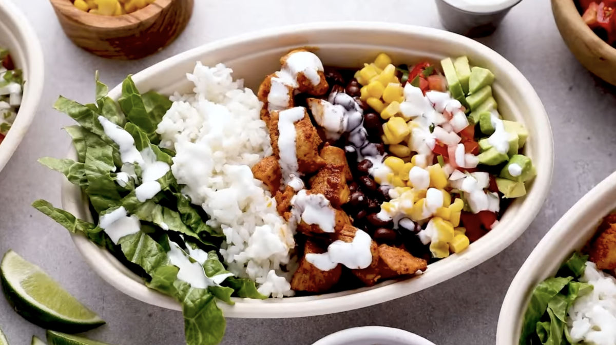 A burrito bowl is presented in an oval shaped bowl. 