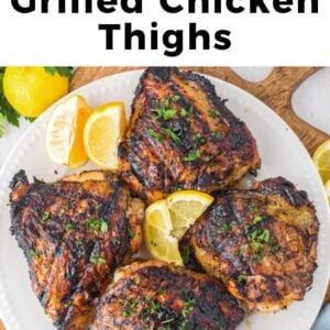 the best grilled chicken thighs on a white plate with lemons.