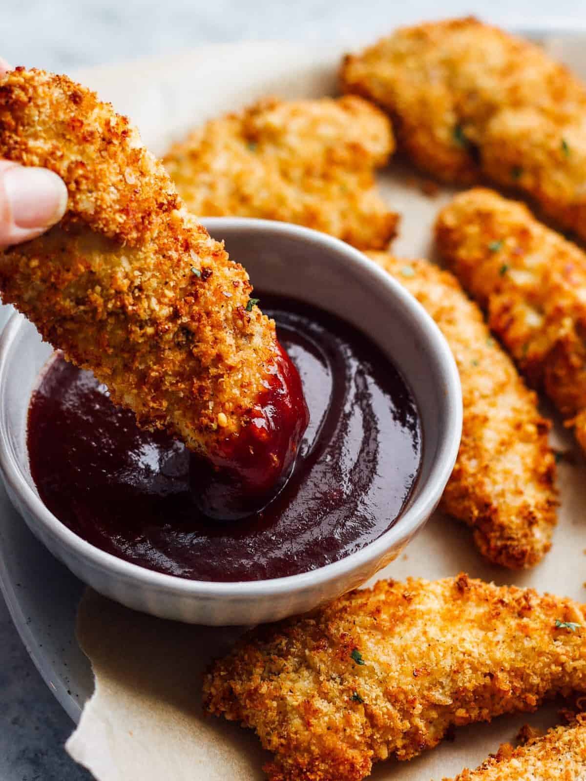 dipping air fried chicken tender in bbq sauce