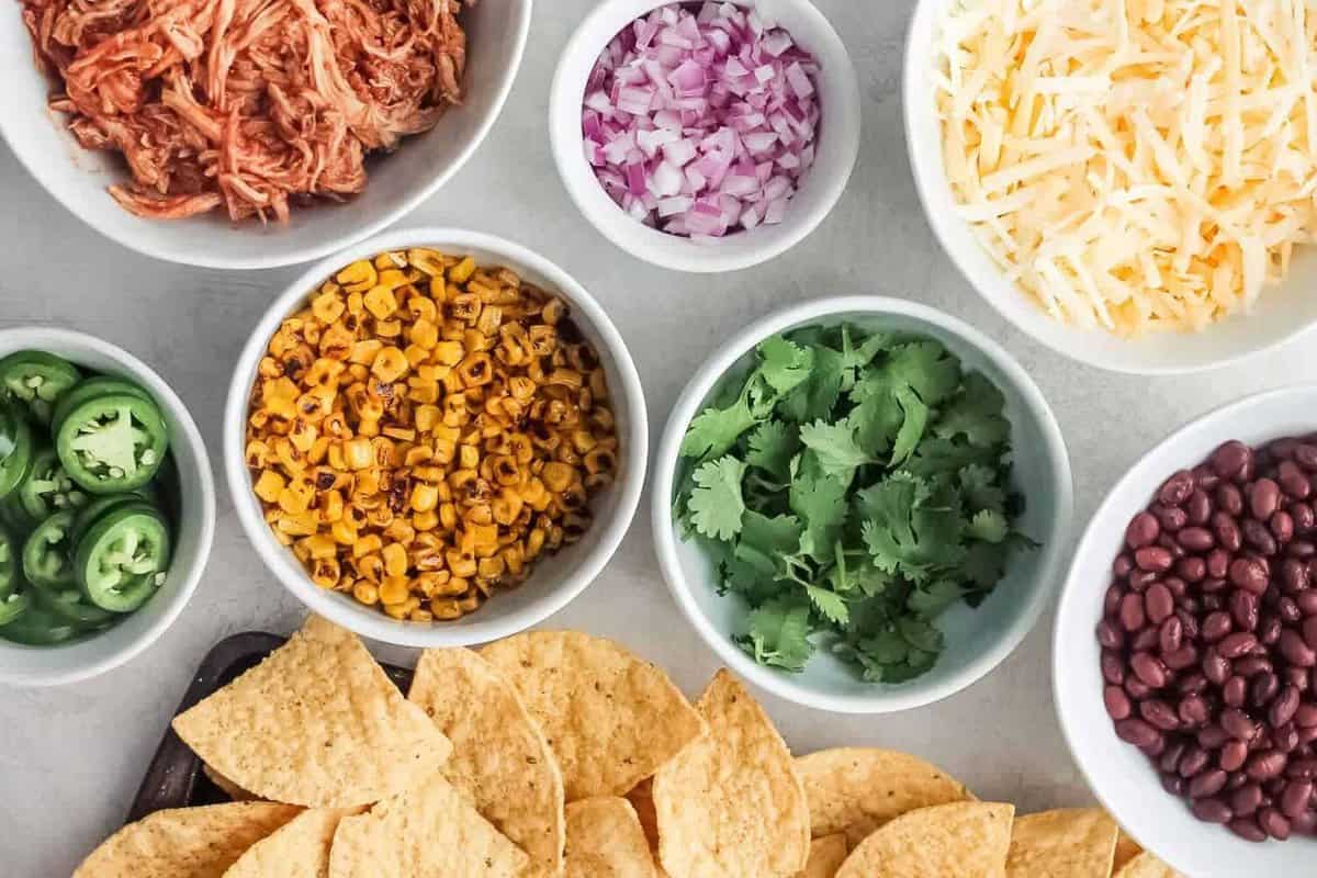 overhead view of BBQ chicken nachos ingredients, separated into bowls