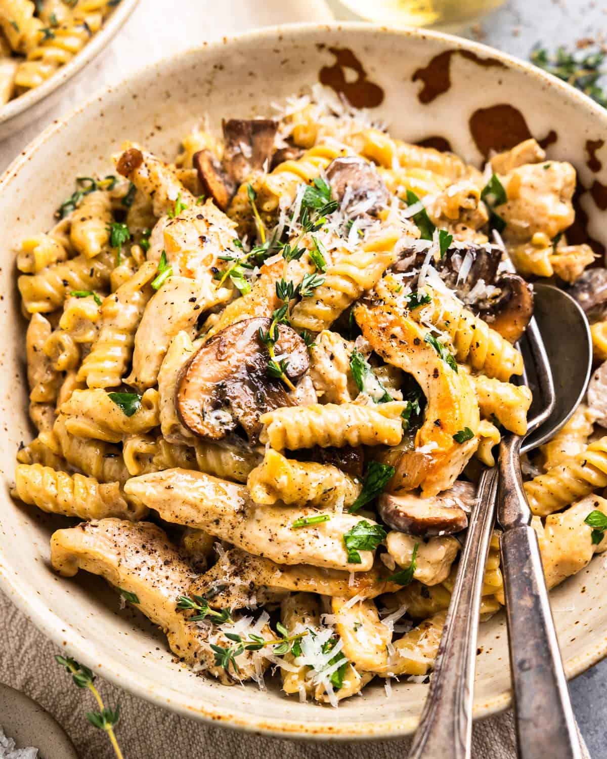 chicken mushroom pasta in a bowl with a fork and spoon.