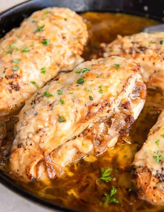 french onion stuffed chicken breasts in a cast iron pan.