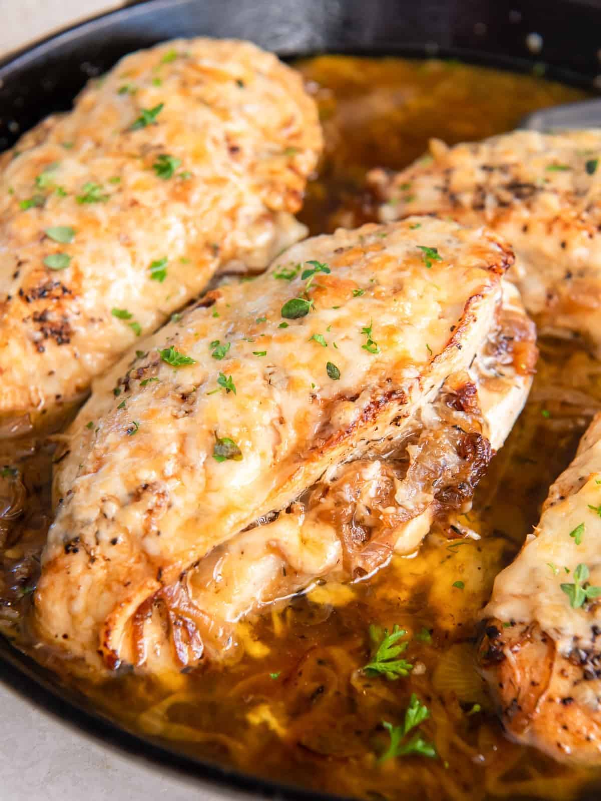 french onion stuffed chicken breasts in a cast iron pan.