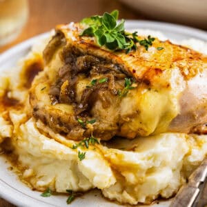 a serving of french onion stuffed chicken on a plate with mashed potatoes.