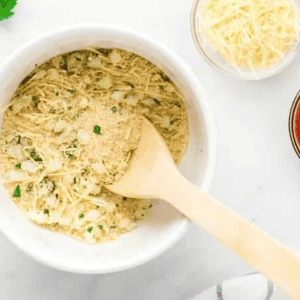 seasoned breadcrumbs in a white bowl with a wooden spoon.