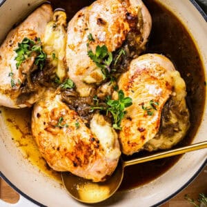french onion stuffed chicken in a pot with a spoon.