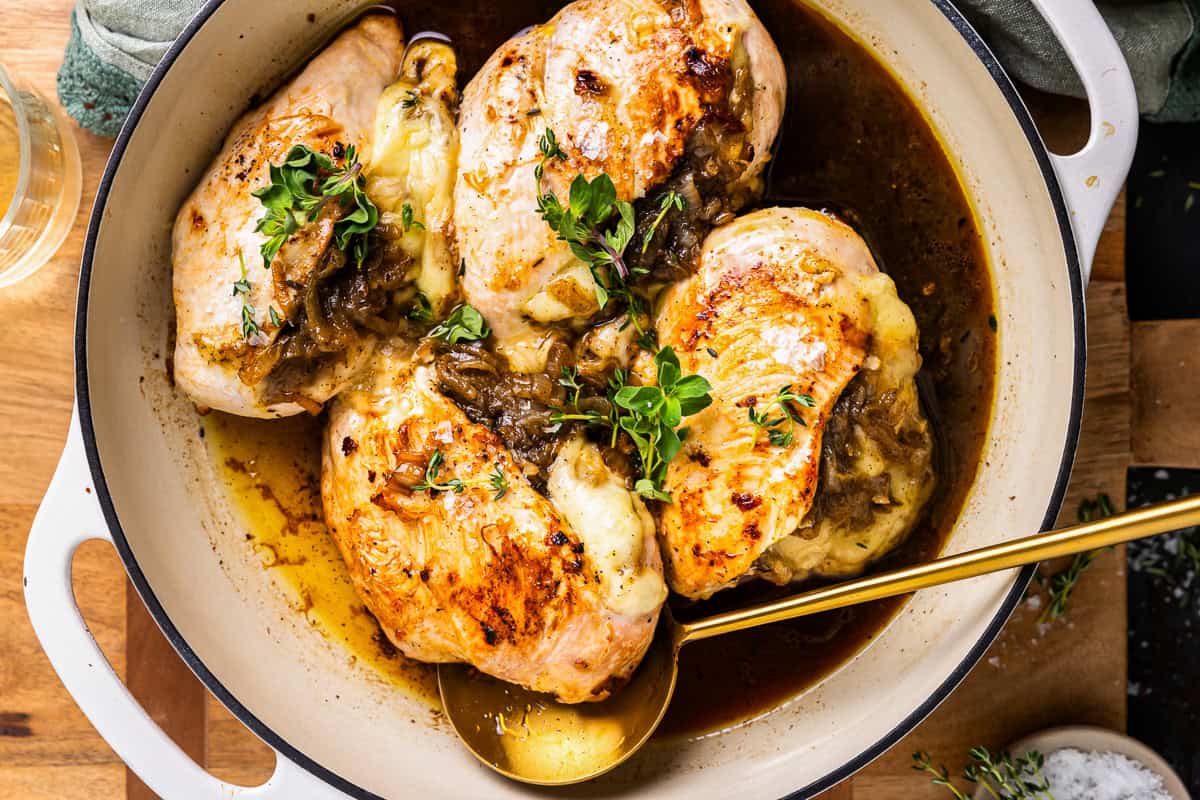 french onion stuffed chicken in a pot with a spoon.