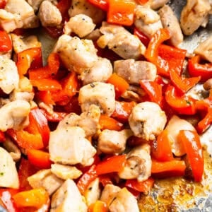 chicken and red pepper chunks cooking in a pan.