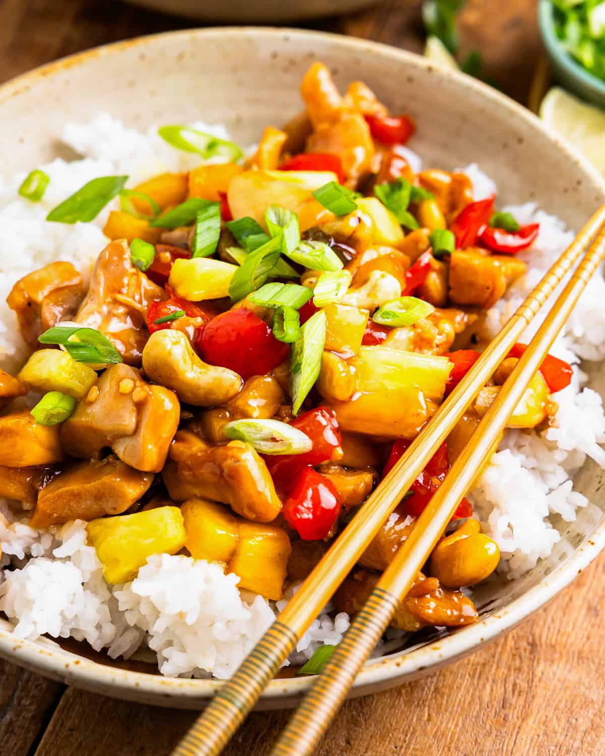 a serving of pineapple chicken in a bowl with rice and chopsticks.