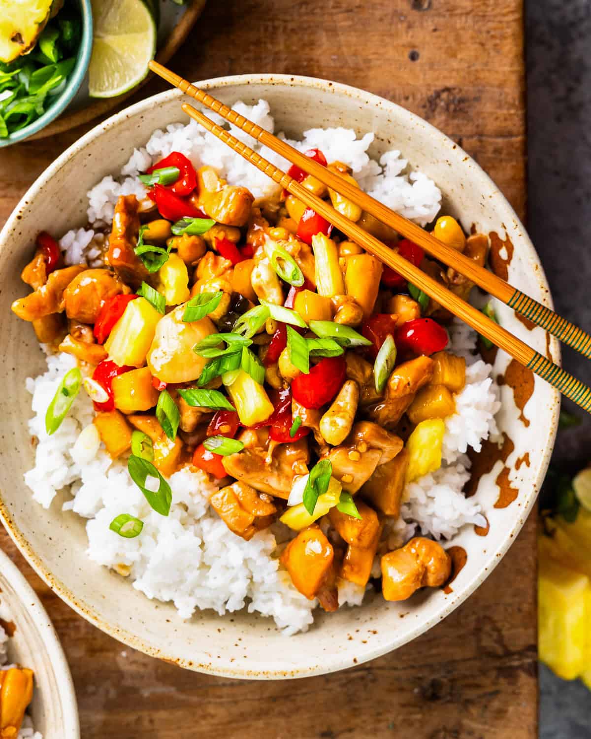 overhead view of a bowl of pineapple chicken over rice with chopsticks.