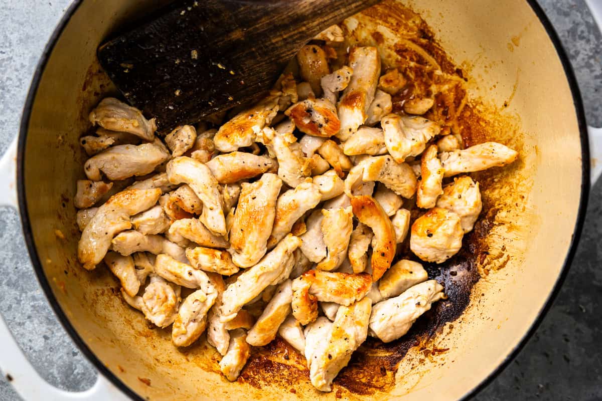 pieces of chicken cooking in a pot.