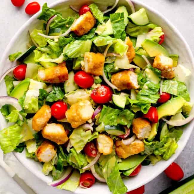 overhead view of a crispy chicken salad with tomatoes and croutons