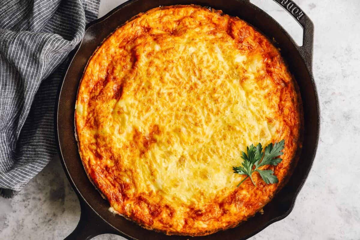 overhead view of a ham and cheese frittata in a cast iron pan.