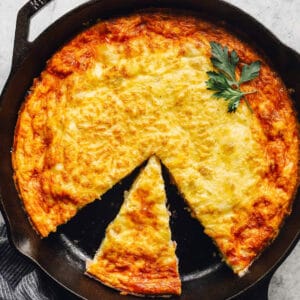 overhead view of a cut ham and cheese frittata with a slice removed.