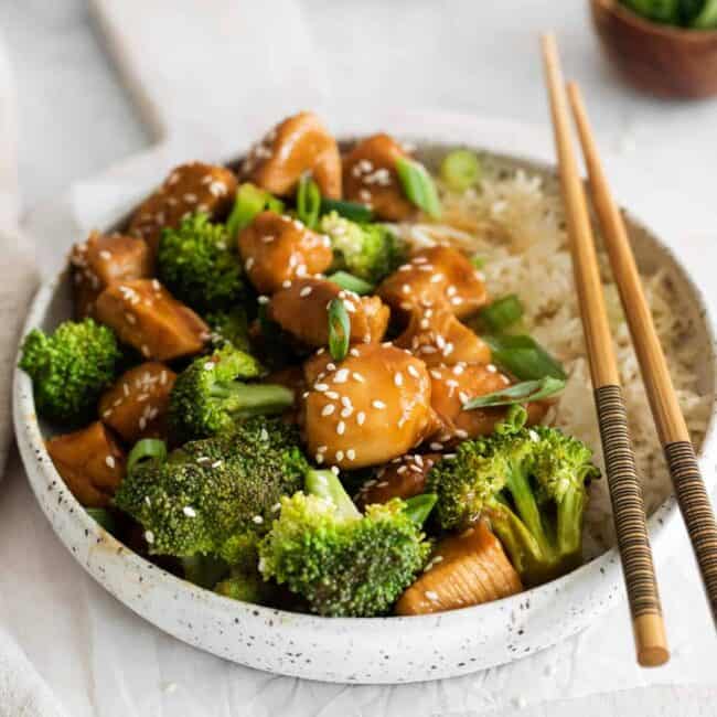 three-quarters view of instant pot chicken teriyaki in a white bowl with white rice and chopsticks.