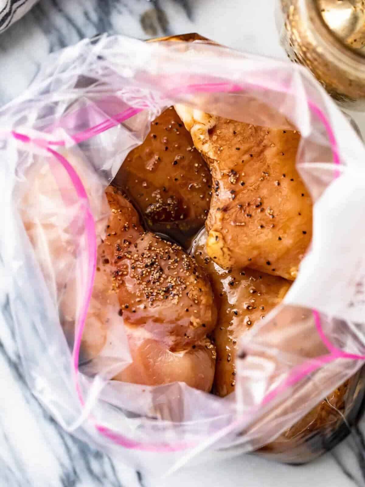 overhead view looking into a resealable bag filled with raw chicken breasts in a lemon pepper balsamic chicken marinade