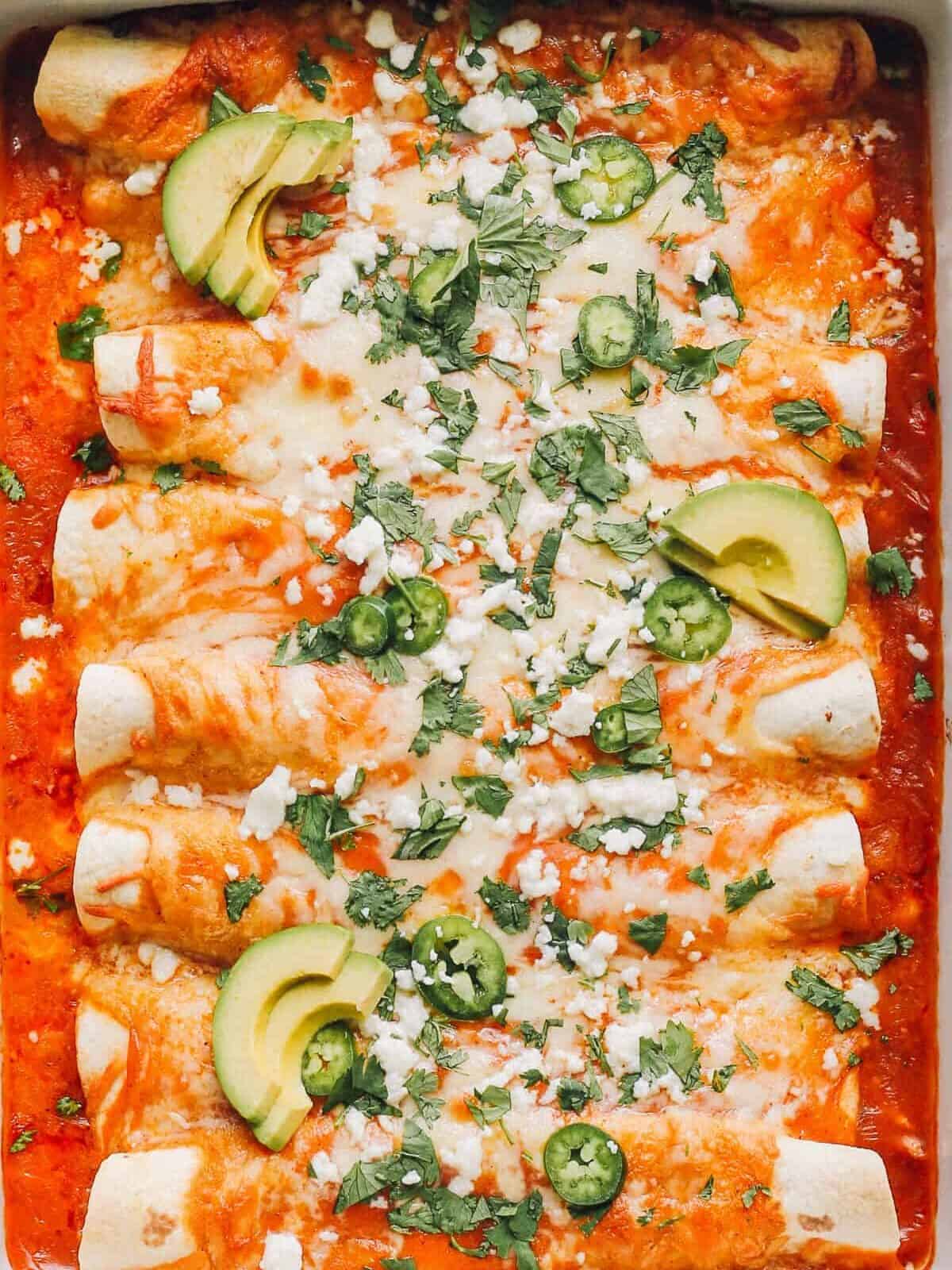 up close image of easy chicken enchiladas garnished with sour cream and cilantro
