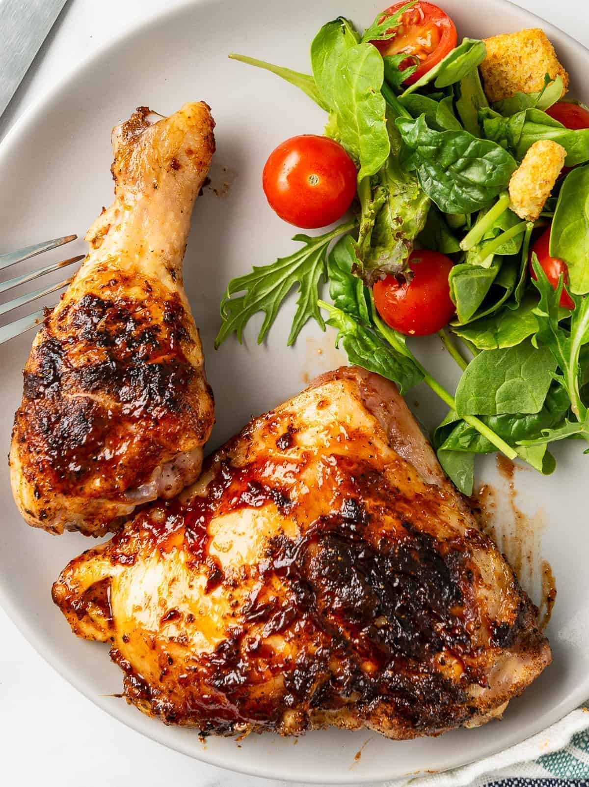 bbq chicken drumstick and thigh on plate with salad